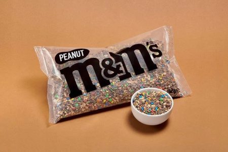 Pojedyncza paczka M&M's Peanut i miseczka pełna kolorowych cukierków z orzechami ziemnymi